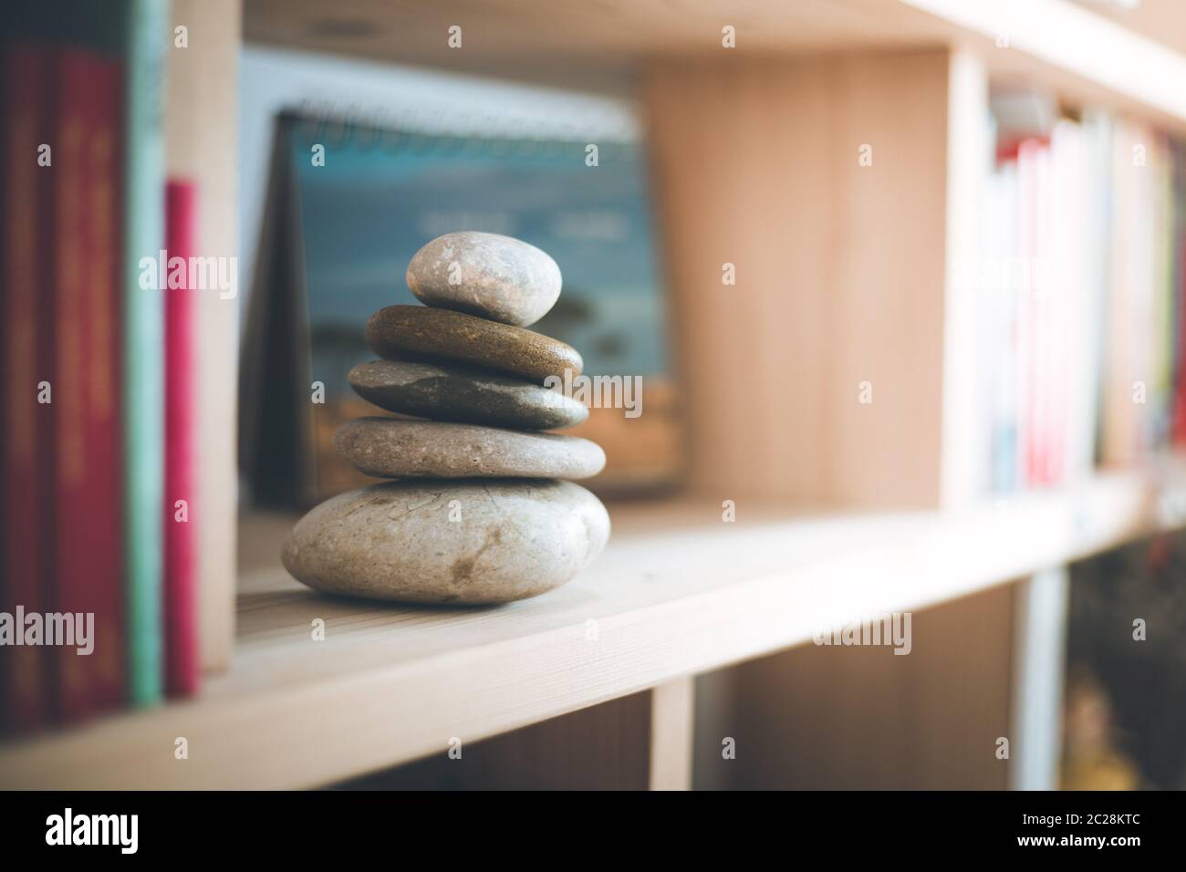 Feng Shui: Cairn de pierre dans un étagère de livre dans le salon, équilibre et détente. Lumière du soleil. Banque D'Images