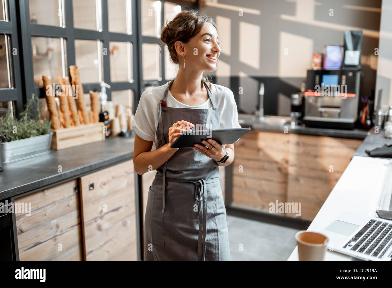 Jeune vendeuse travaillant avec une tablette numérique au comptoir d'un café ou d'un magasin de confiserie. Concept de petite entreprise et technologies dans le domaine des services Banque D'Images