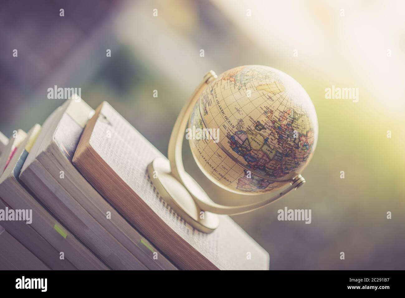 Planifier le prochain voyage : un globe miniature sur une pile de livres. Banque D'Images