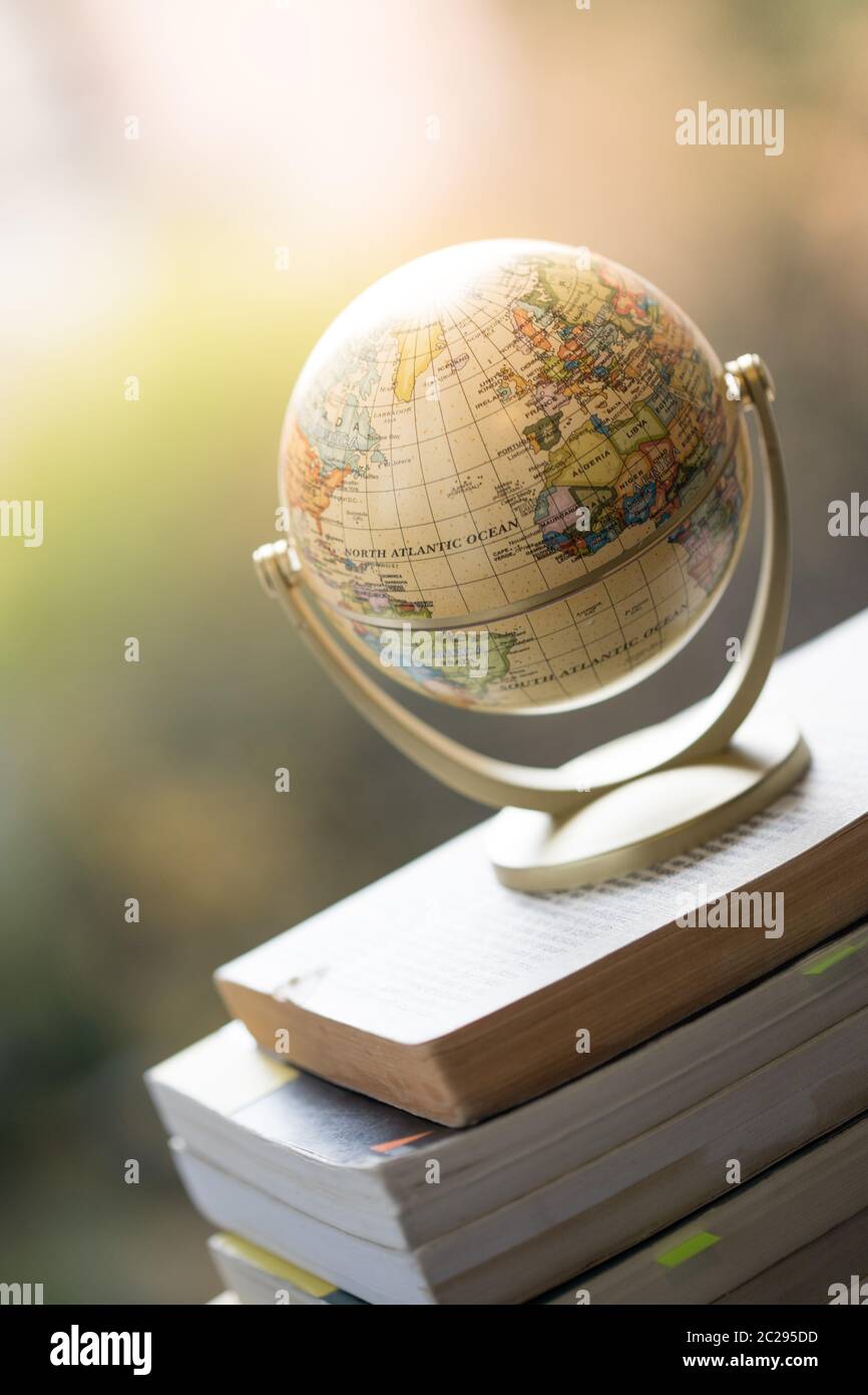 Planifier le prochain voyage : un globe miniature sur une pile de livres. Banque D'Images
