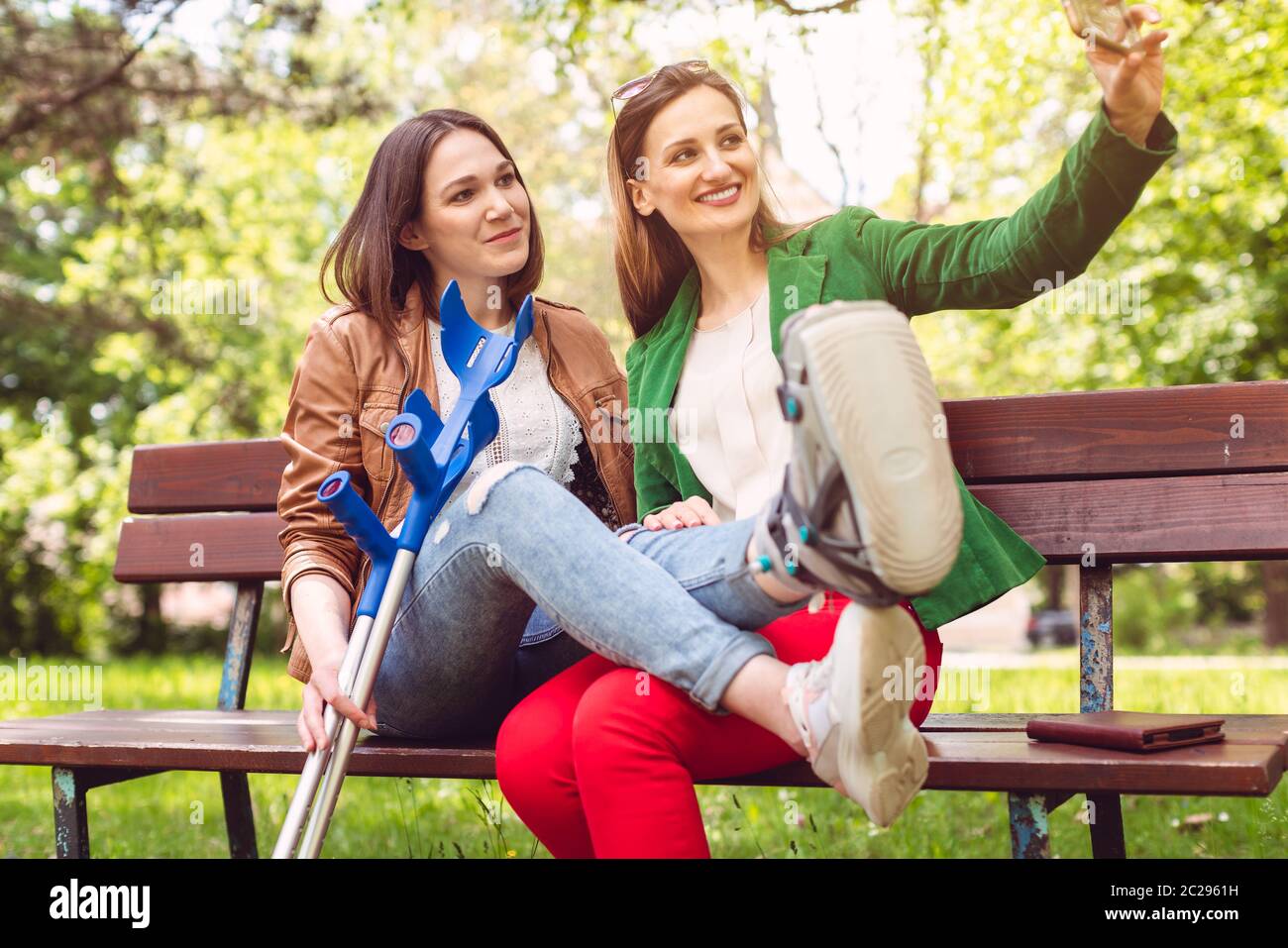 Meilleurs amis avec un ayant une jambe cassée prenant un selfie au téléphone Banque D'Images