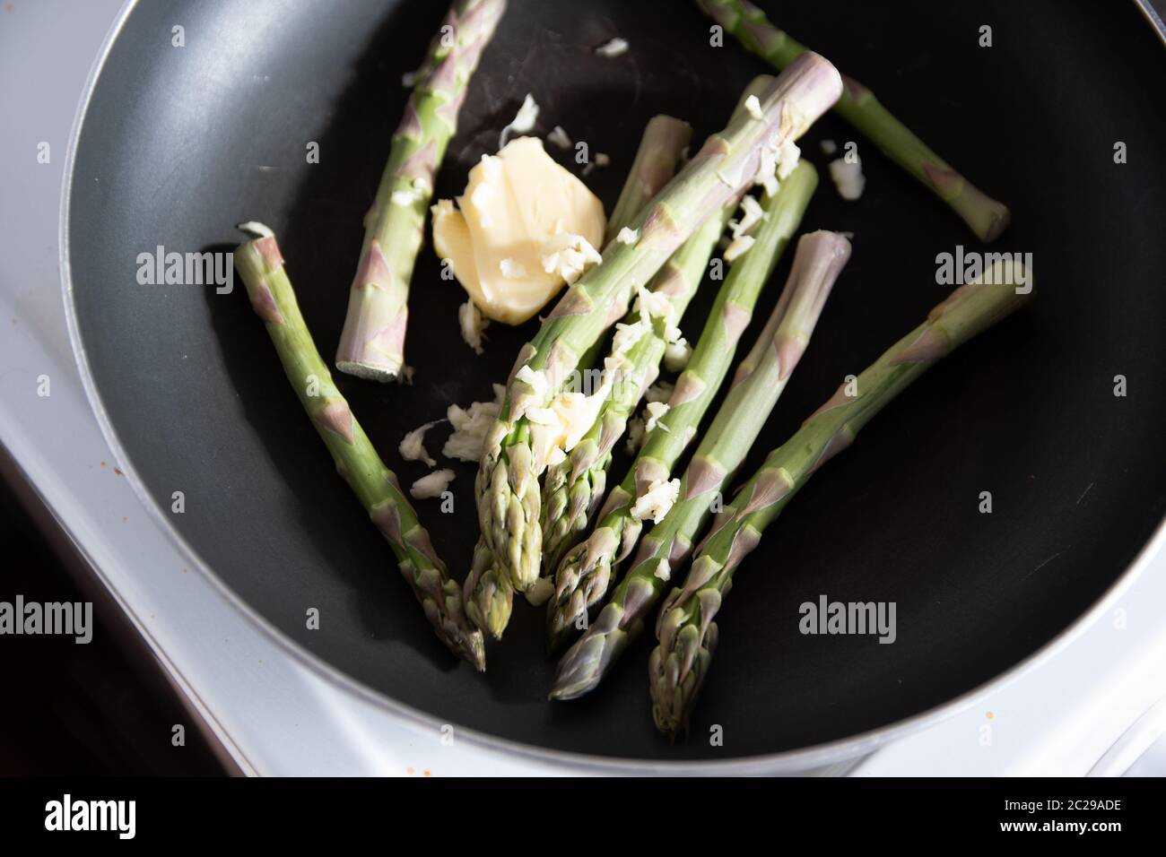 Quelques asperges vertes fraîches cuisant et friture dans une poêle sur le ho Banque D'Images