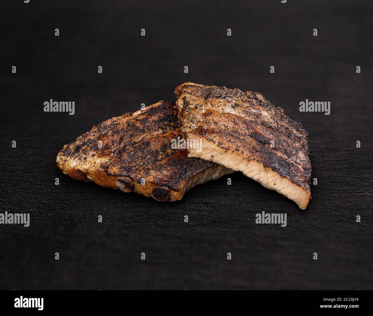 Côtes levées fumées et grillées sur fond noir Banque D'Images