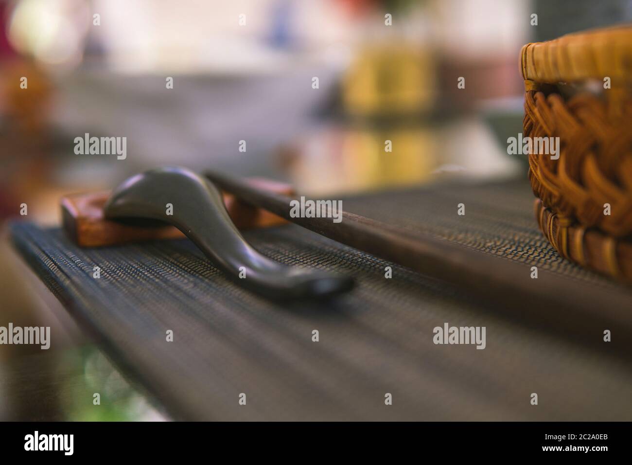 Gros plan d'une cuillère en bois et de baguettes à côté d'un bol de riz en rotin, à l'intérieur se trouve un déjeuner traditionnel vietnamien, du riz, de la soupe, des aliments salés. Banque D'Images