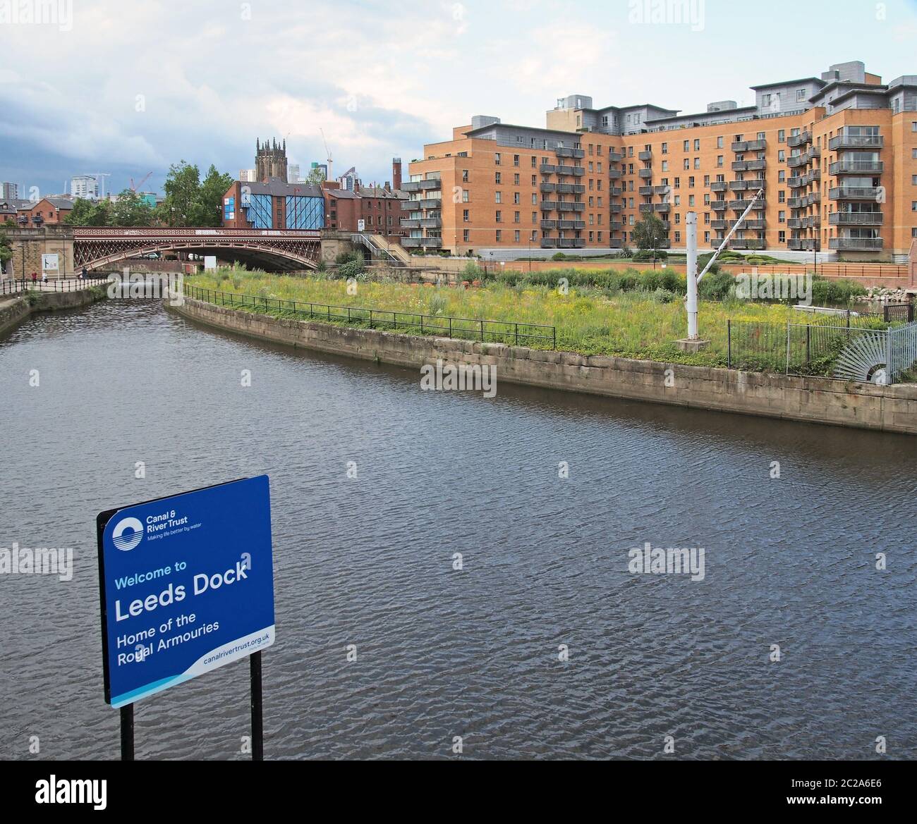 vue sur le bord de mer de leeds près de l'entrée du quai avec panneau à côté du canal et appartements au bord de l'eau avec le minster et la ville ce Banque D'Images