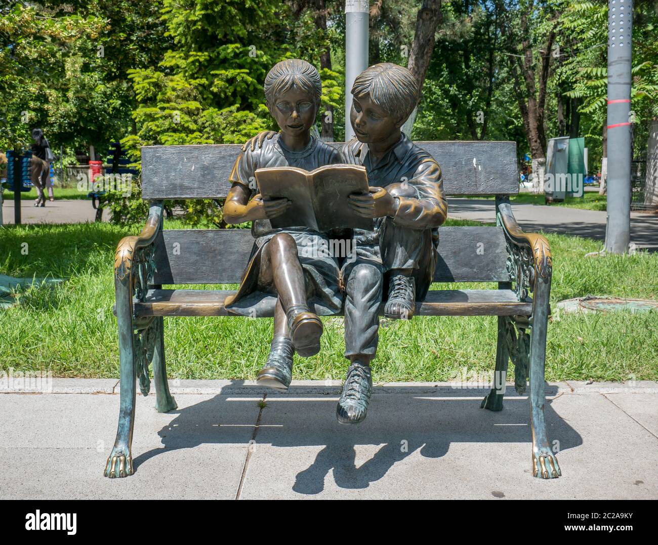 Bucarest/Roumanie - 05.30.2020: Statue en bronze d'une fille et d'un garçon lisant un livre sur un banc. Banque D'Images