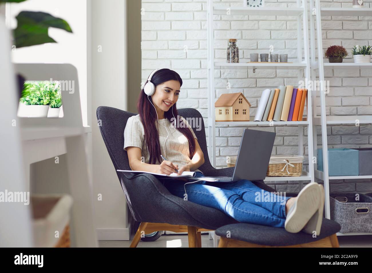 Une jeune femme étudiante assiste à un cours en ligne, à un webinaire ou à une conférence Internet depuis sa maison à l'aide d'un ordinateur portable Banque D'Images