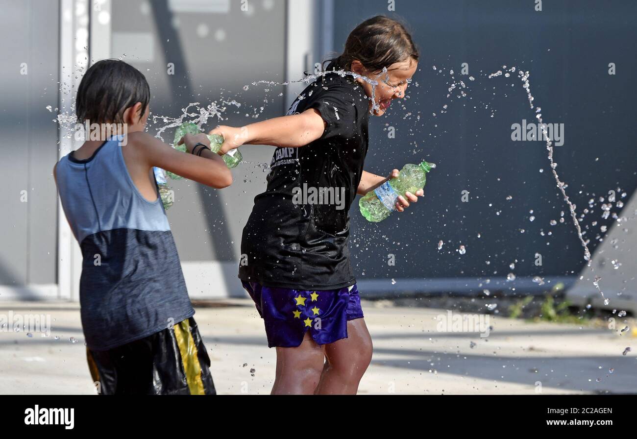 Camp d'été enfants jouant avec des bouteilles d'eau pour se rafraîchir, pendant une chaude journée d'été, à Milan. Banque D'Images