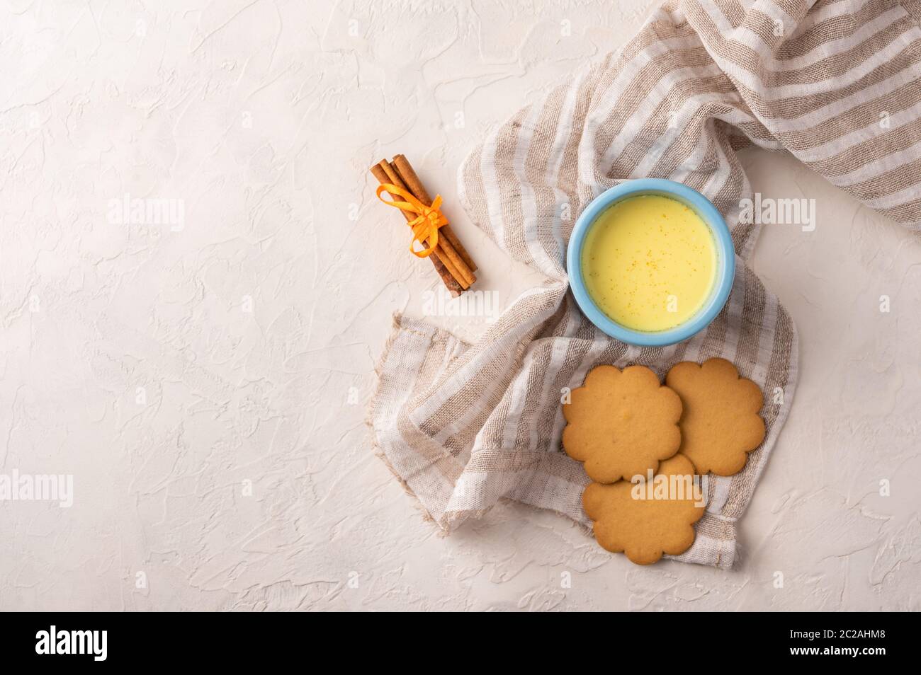 Deux tasses bleues avec thé traditionnel indien masala chai, bâtonnets de cannelle et biscuits sur une serviette en lin sur fond clair. Vue de dessus avec espace de copie Banque D'Images