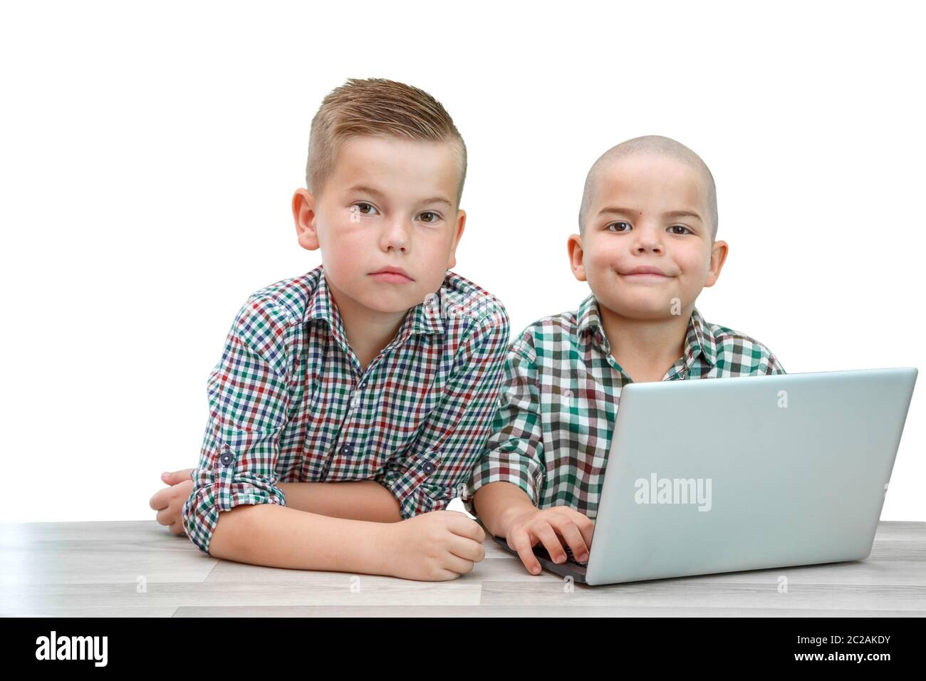 Deux garçons de race blanche ,frères sur un arrière-plan blanc isolé. enseigne, à l'autre d'utiliser un ordinateur portable. Banque D'Images