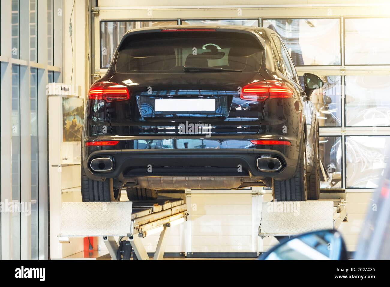 Voiture sur un élévateur de parallélisme en auto service dans un garage moderne. Diagnostic du châssis de la voiture relevée à l'ascenseur Banque D'Images