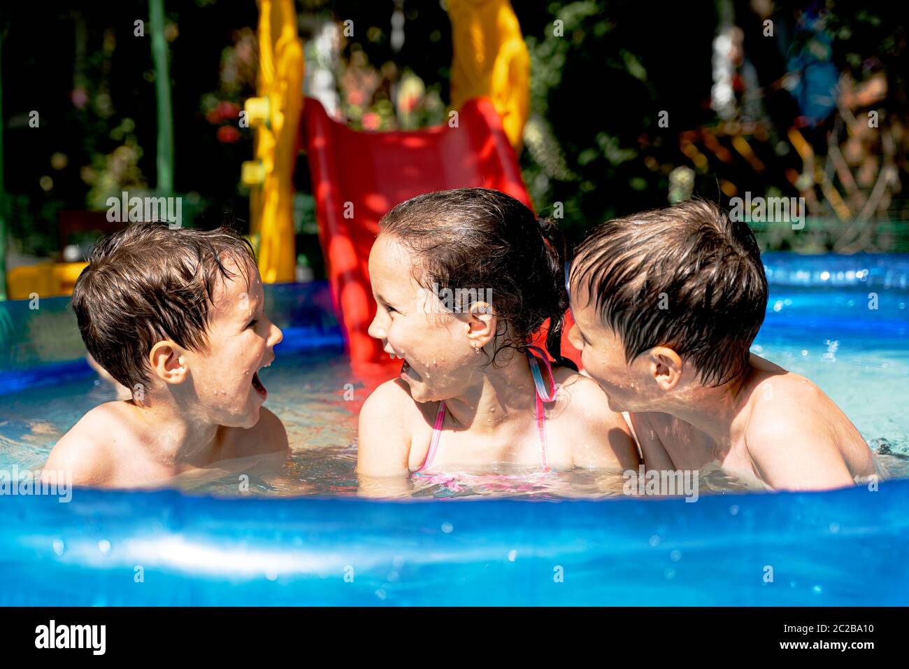 les enfants heureux et en bonne santé nagent dans la piscine en été et rient Banque D'Images