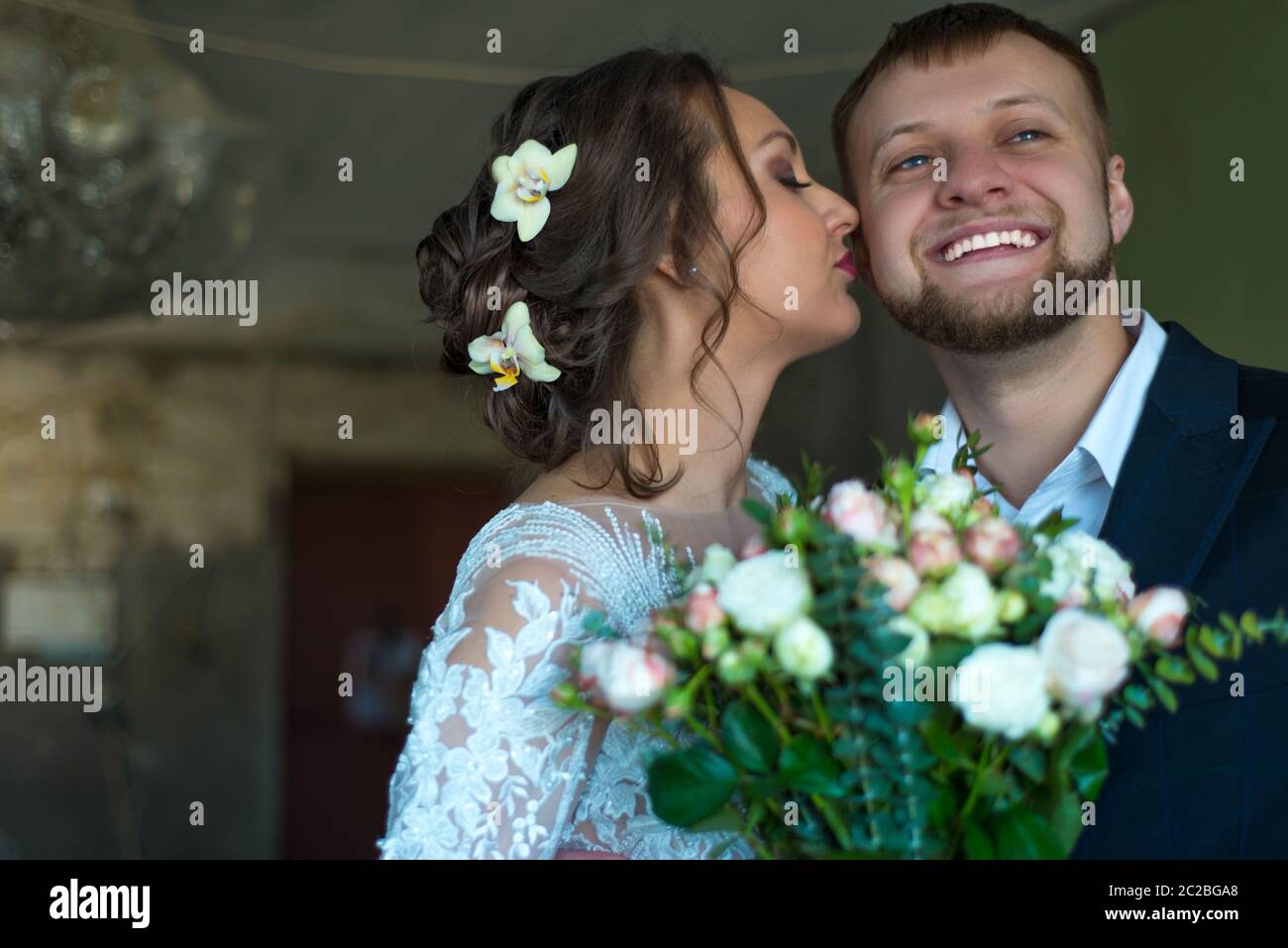 Portrait de la mariée et du marié heureux. La mariée embrasse le marié. Jeunes souriants de vingt-cinq ans, cérémonie de mariage, couple de mariés Banque D'Images