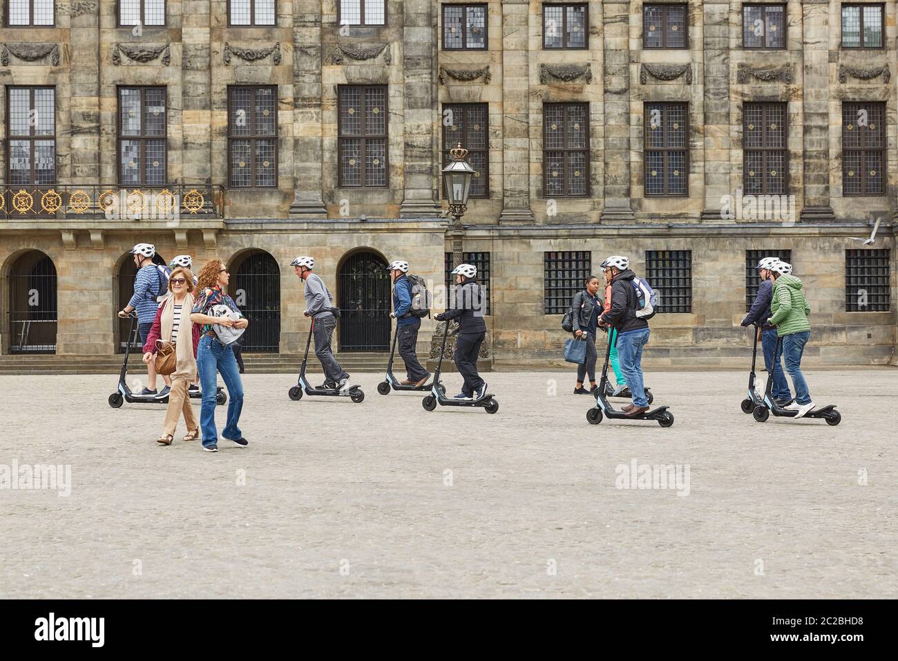 Les gens qui font du scooter en face du Palais Royal et en passant par le centre d'Amsterdam pays-Bas Banque D'Images