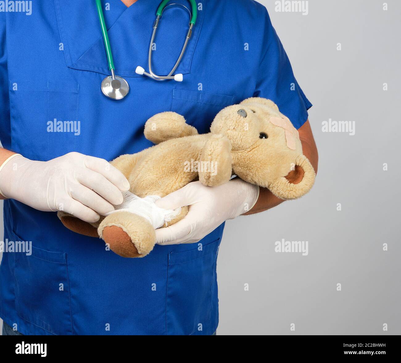 Médecin en uniforme bleu blanc bandages bandage médical paw ours en peluche brun, fond blanc Banque D'Images