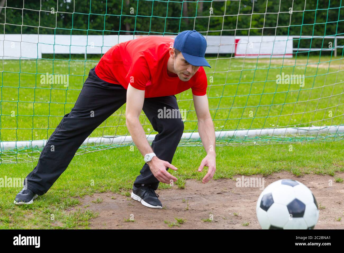 Jeune homme à la pac comme gardien de la capture d'un ballon de soccer sur un terrain de soccer Banque D'Images
