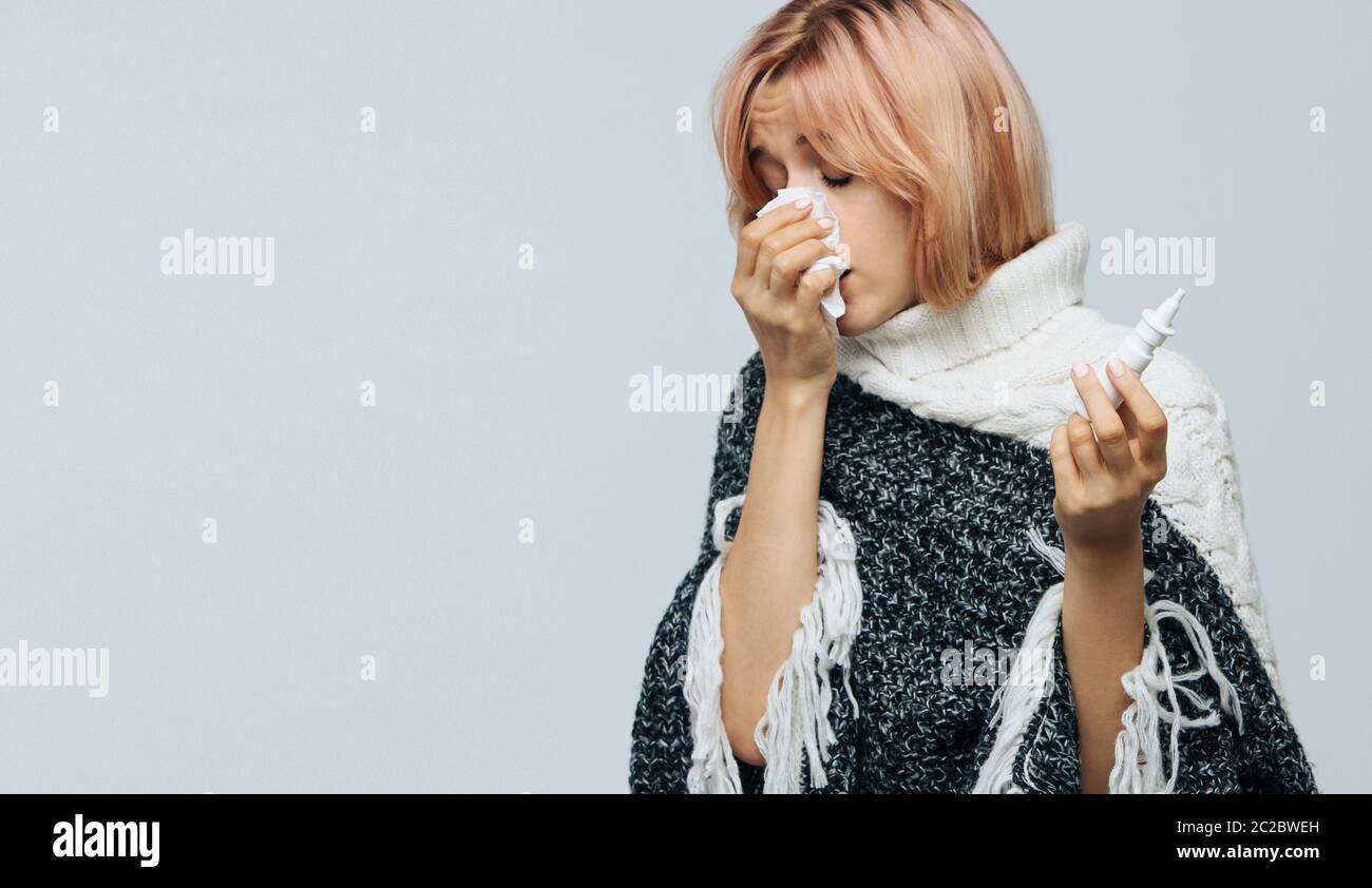 Portrait de studio de la femme caucasienne cute malsaine avec papier serviette éternuer, en utilisant le spray nasal pour se aider, éprouve des symptômes d'allergie, attrapé Banque D'Images