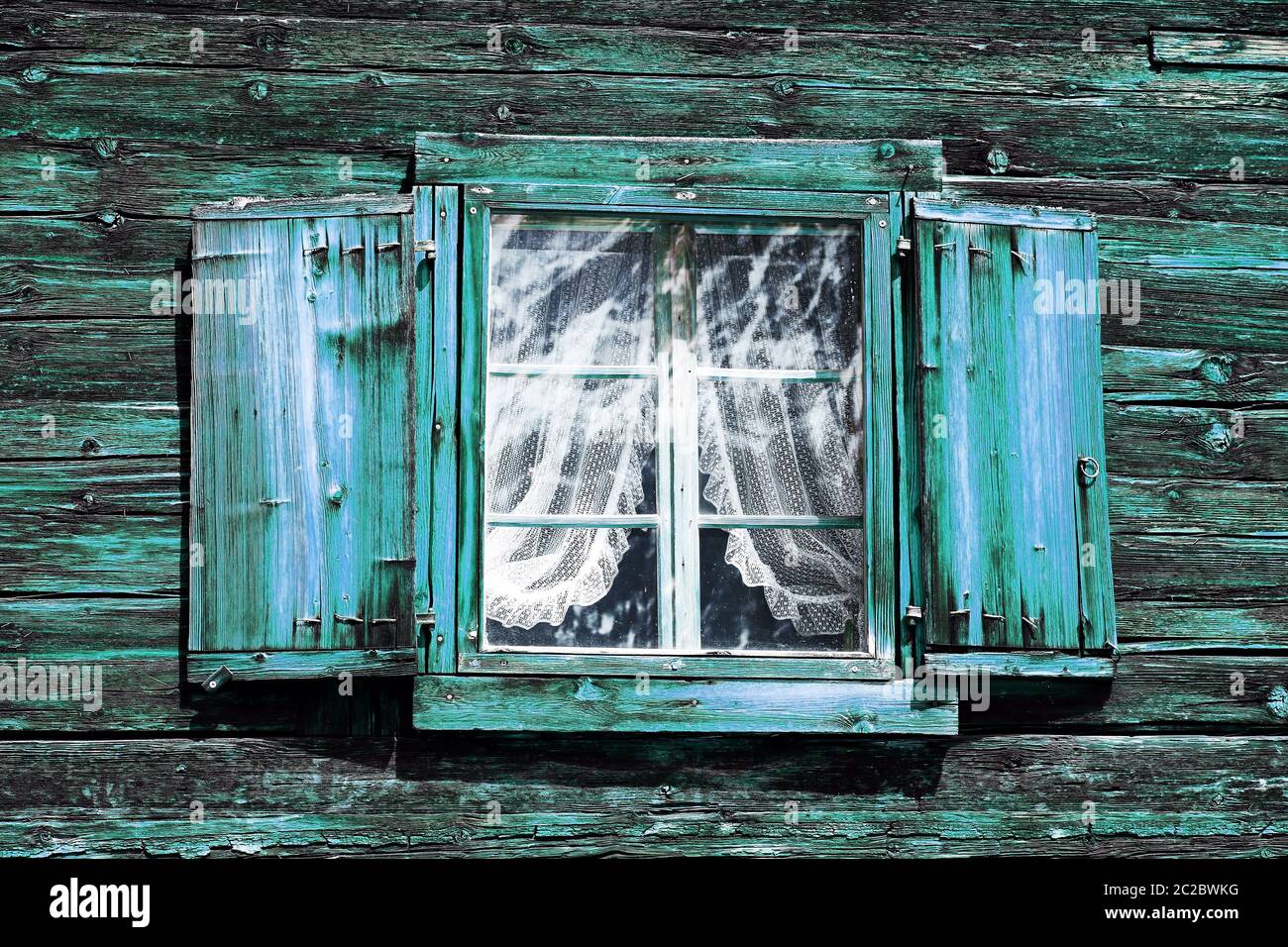 Fenêtres avec rideaux et volets dans une ancienne maison en bois vert-bleu Banque D'Images