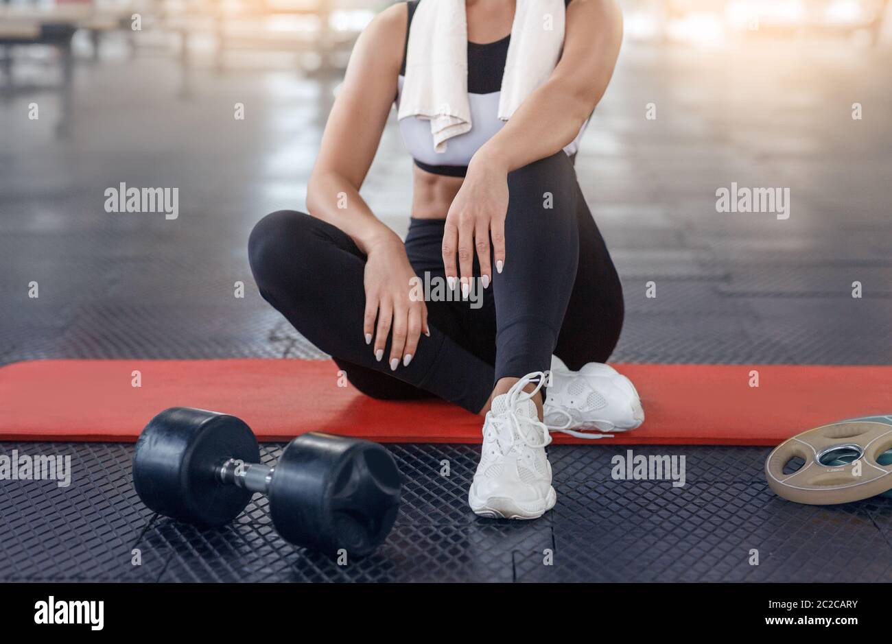 Femme méconnue se reposant après son entraînement de force sur le sol à la salle de gym, gros plan Banque D'Images