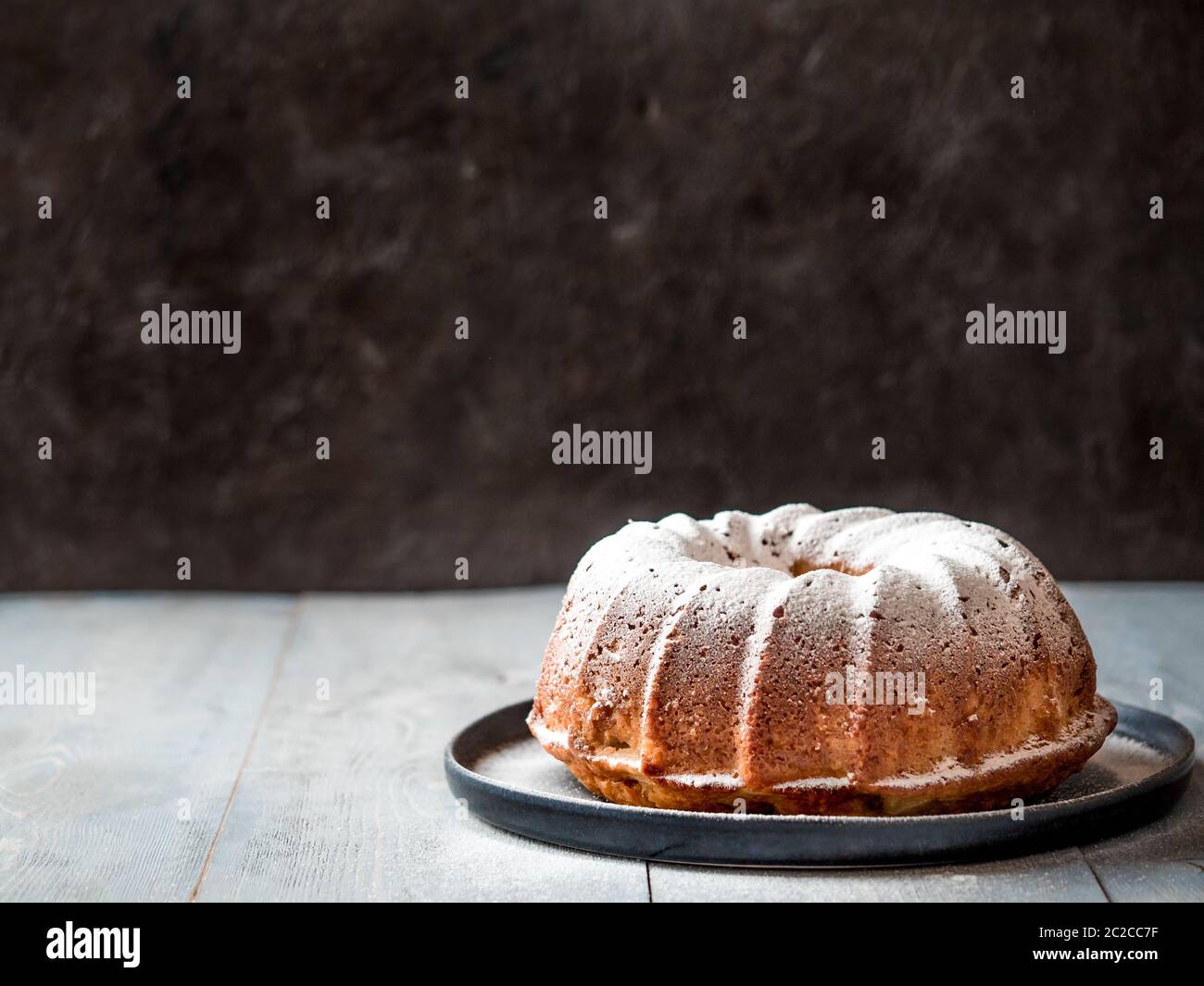 Saupoudrer le sucre glace à la main sur le gâteau au muffin Banque D'Images