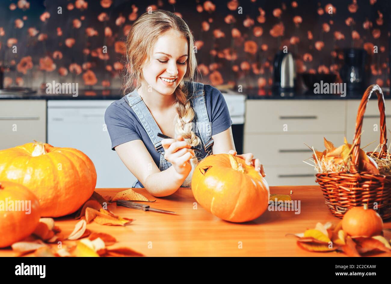 une belle femme blonde peint des citrouilles pour halloween à la maison sur la cuisine Banque D'Images