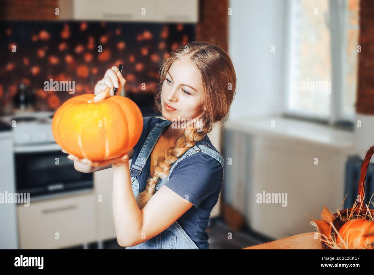 une belle femme blonde peint des citrouilles pour halloween à la maison sur la cuisine Banque D'Images