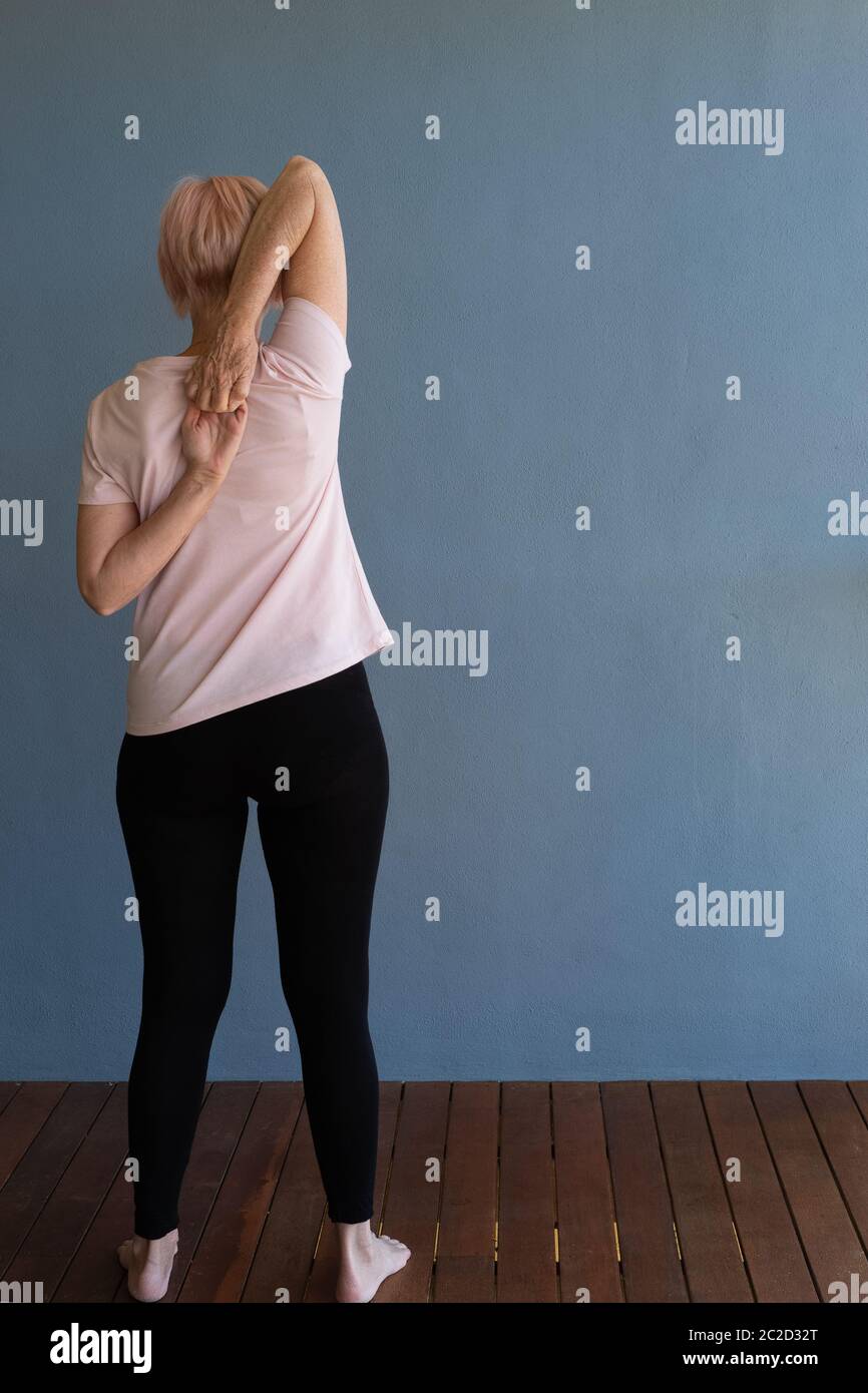 Femme âgée qui s'étire pour rester en forme à la maison Banque D'Images