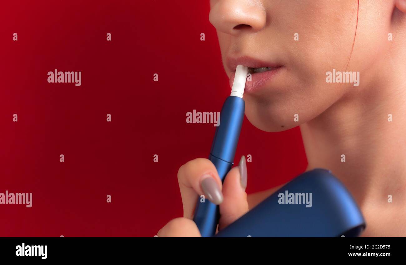 Cigarette électronique sur les lèvres femelles. Système IQOS du tabac. Gros  plan d'une fille fume une cigarette électrique hybride avec un bloc  chauffant. Chauffage du tabac Photo Stock - Alamy