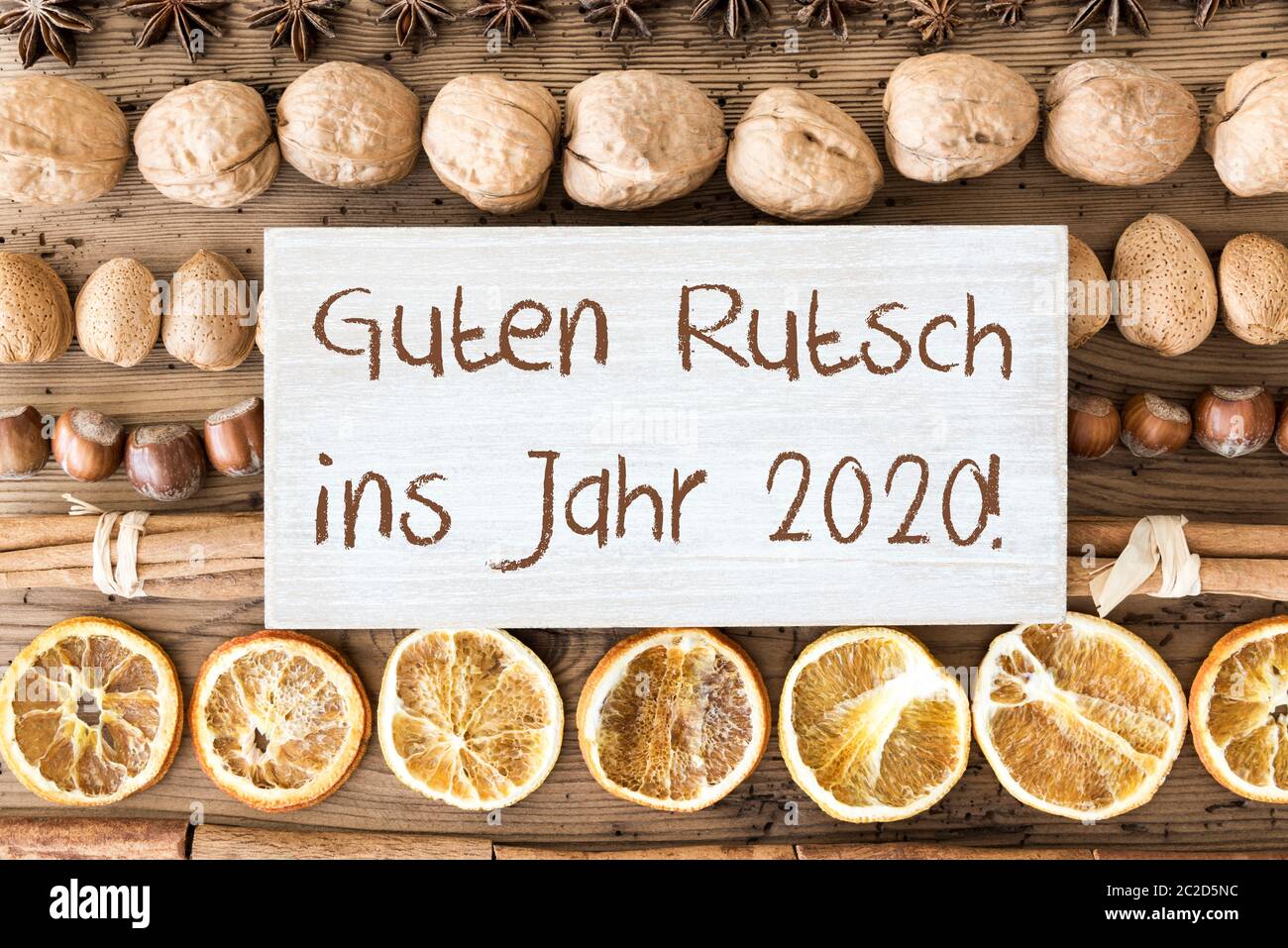 Signer avec le texte allemand Guten Rutsch ins Jahr 2020 signifie bonne année 2018. Plat de Noël avec noix, noisettes, bâtons cannelle et orange Banque D'Images
