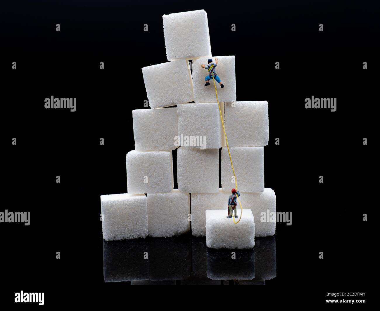 Les grimpeurs miniatures grimpent sur une pile de blocs de sucre Banque D'Images