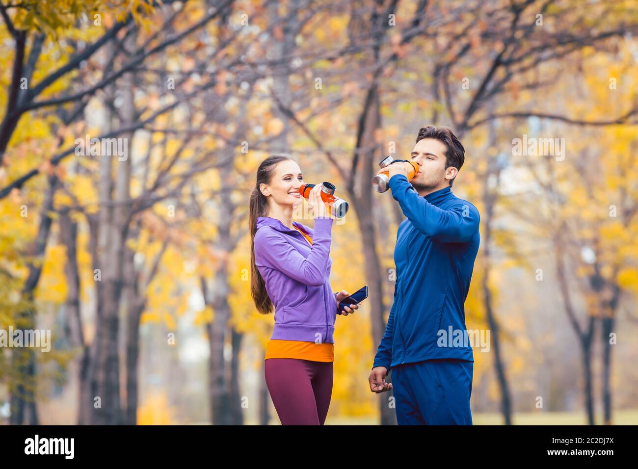 Couple sportif qui boit de l'eau rafraîchissante après une pause de la course Banque D'Images