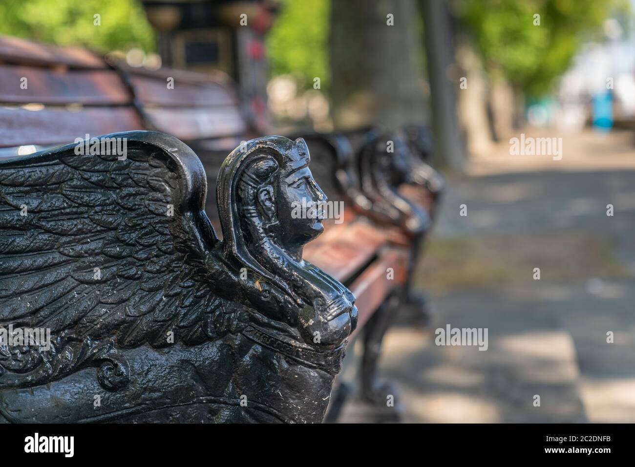 Banc de lattes en bois de fonte sur l'Embankment orné d'une tête Sphinx à ailes noires surplombant majestueusement la Tamise à Londres, en Angleterre Banque D'Images