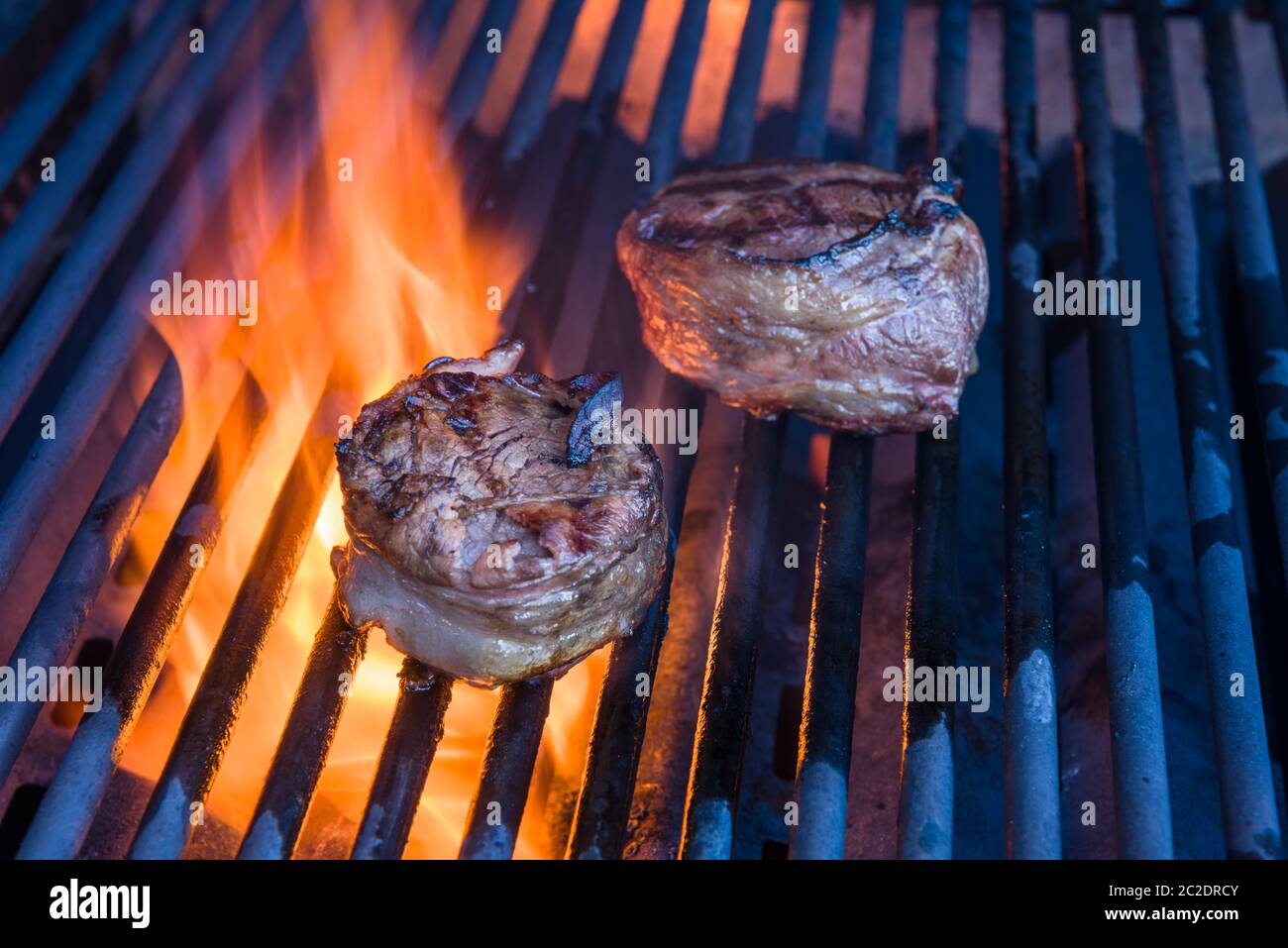 Une paire de filet mignon enveloppé de bacon et cuisant un grill avec une flamme Banque D'Images
