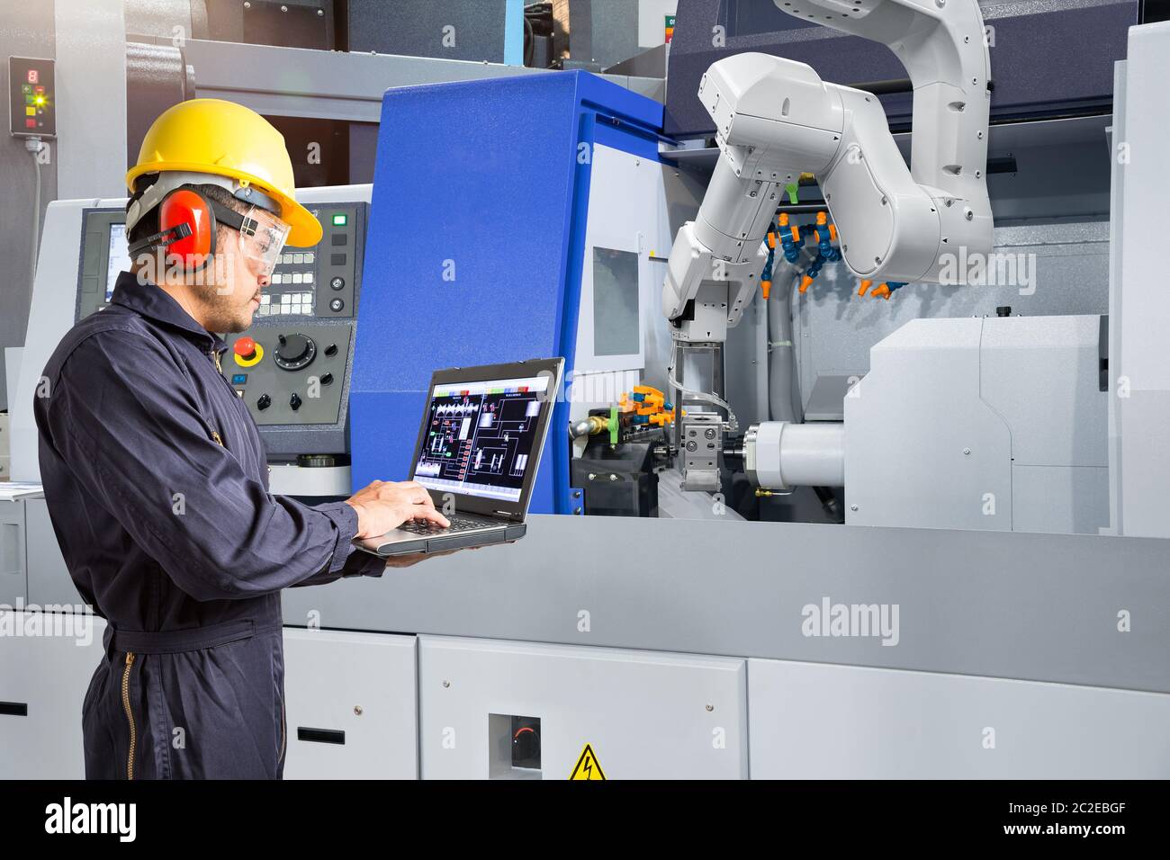Ingénieur de maintenance en utilisant un ordinateur portable contrôle automatique main robotique avec machine CNC dans smart factory, de l'industrie 4.0 concept Banque D'Images
