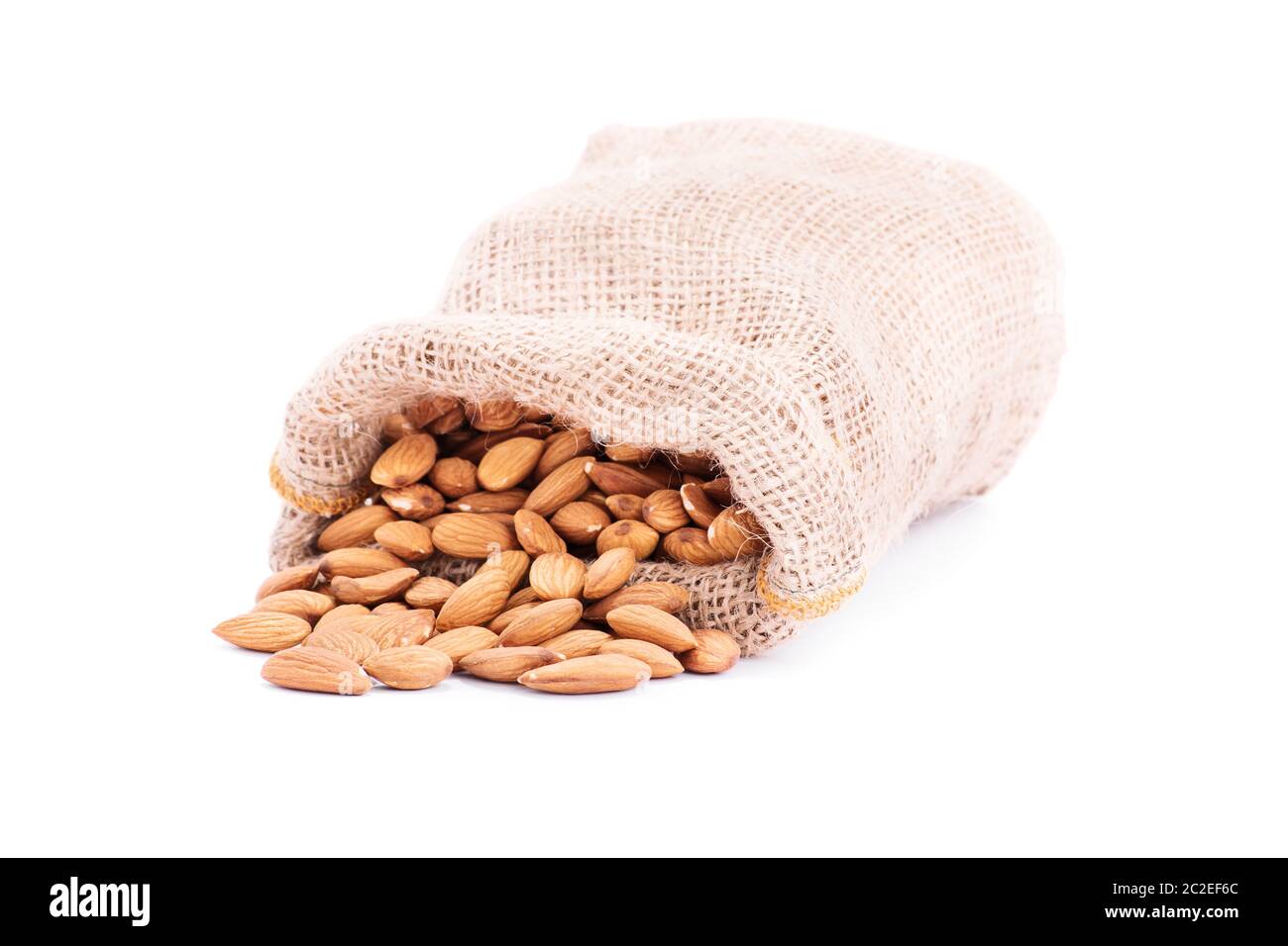 Gros plan du sac de jute renversé d'amandes, isolé sur fond blanc. Banque D'Images