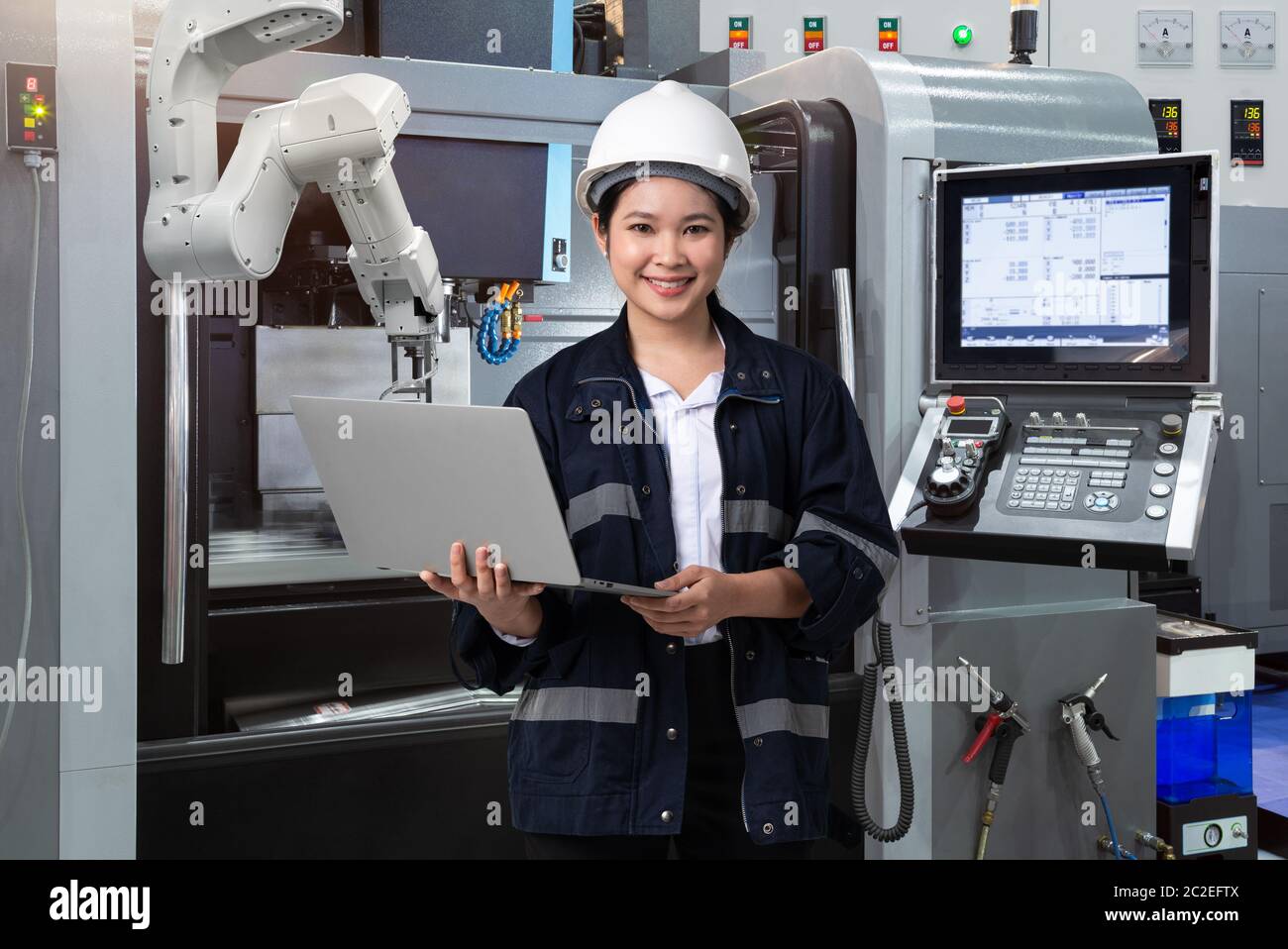 Maintenance femme ingénieur utilisant ordinateur portable contrôle automatique main robotique avec machine CNC dans l'usine intelligente, Industry 4.0 concept Banque D'Images