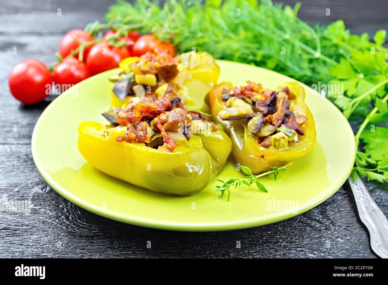 Poivron farci aux champignons, tomates, courgettes, aubergines et oignons, assaisonnés avec du vin, l'ail, le thym et les épices dans un livre vert sur la plaque de sol en bois Banque D'Images