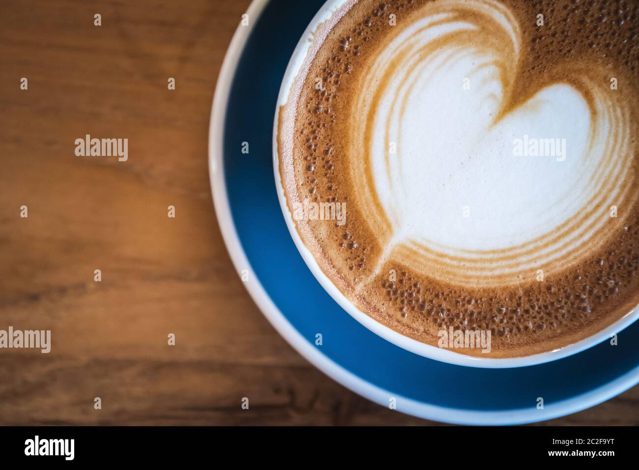 Magnifique une tasse bleue de cappuccino chaud avec art latte sur table de café en bois, foyer sélectif pour boire le fond Banque D'Images