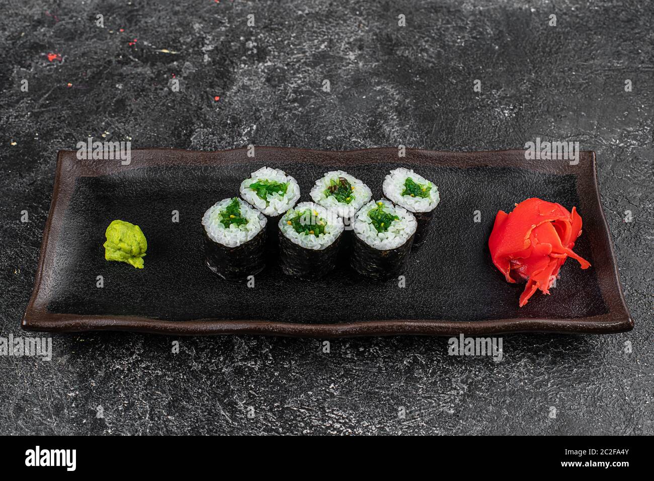 Petits pains à sushis avec fruits de mer et salade Chuka. Sushis verts. Vue de dessus. Espace libre pour votre texte. Banque D'Images