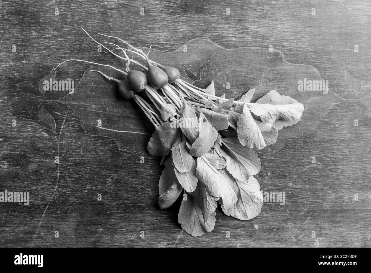 Radis rouge sur une table en bois. Légumes rouges avec feuilles vertes. Banque D'Images