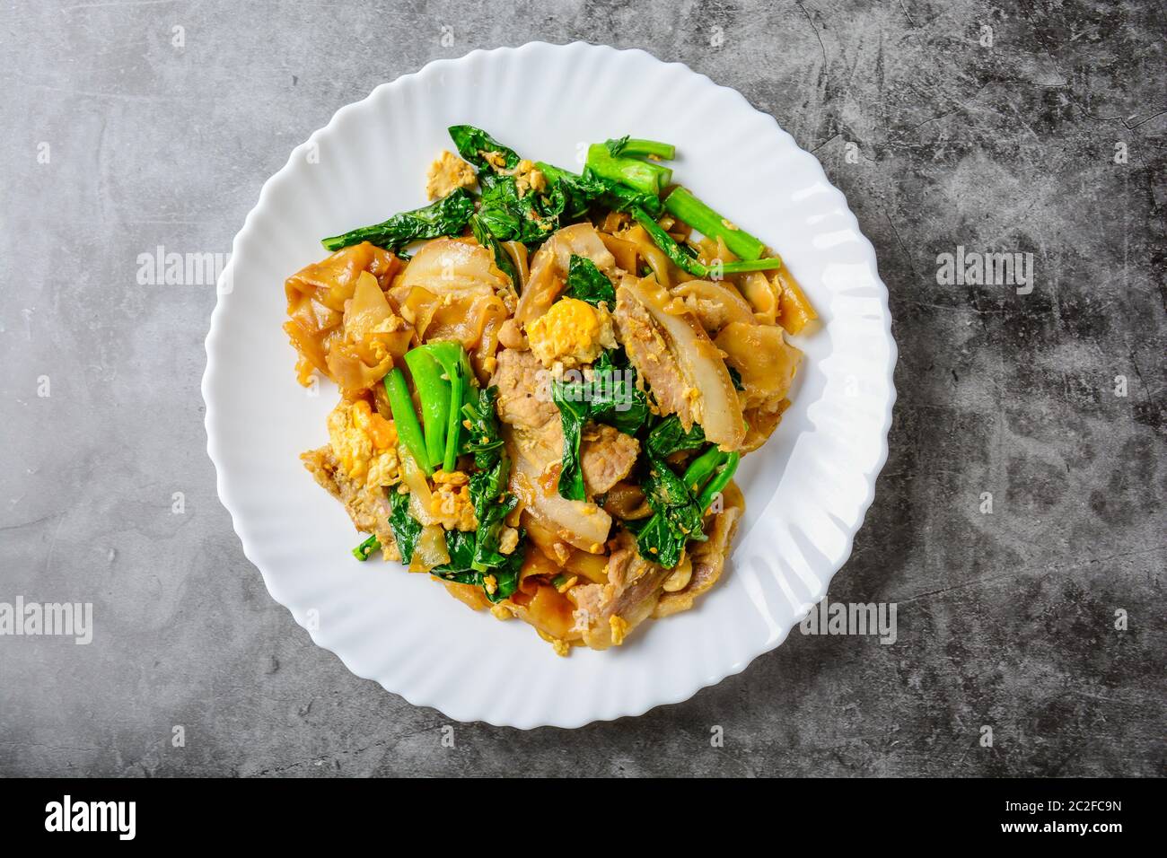 Sauté de nouilles de farine de riz frais avec des tranches de porc, d'oeufs et de chou frisé. Sauté de nouilles rapide. Banque D'Images