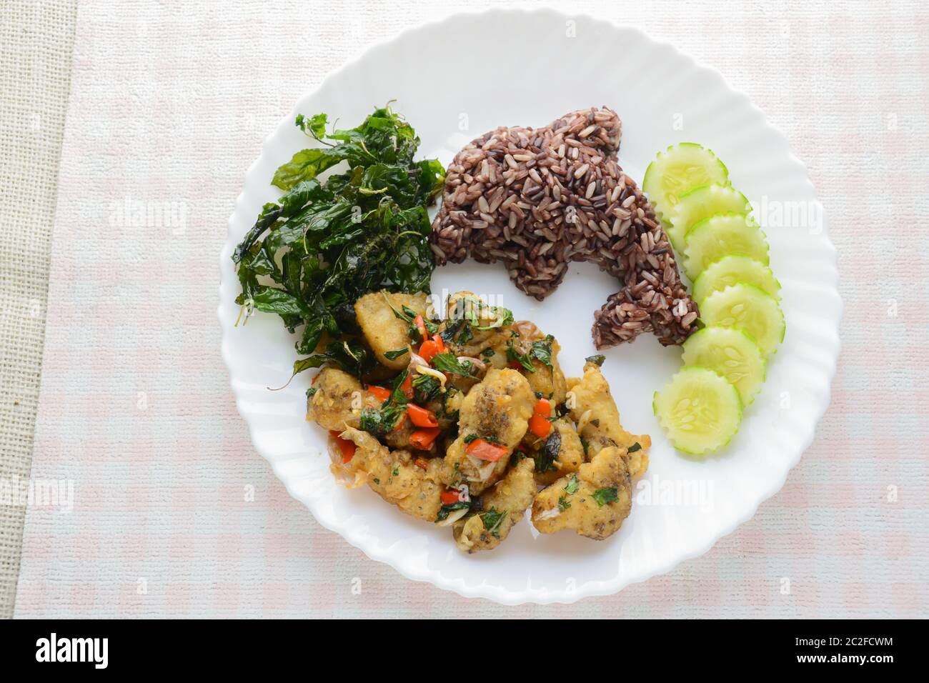 Mélangez le poisson frit au piment et au basilic, servi avec du riz et du concombre cuits à la vapeur, un plat chaud et épicé. Banque D'Images