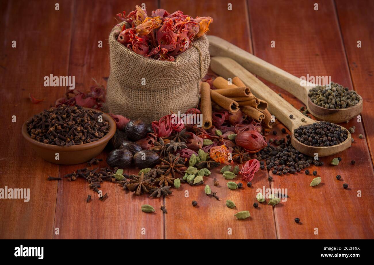 Épices séchées poivre noir,poivre vert,Mace ou fleur de javiithri,muscade,Clove,cannelle,cardamome,Anis étoilé disposés sur une surface en bois Banque D'Images