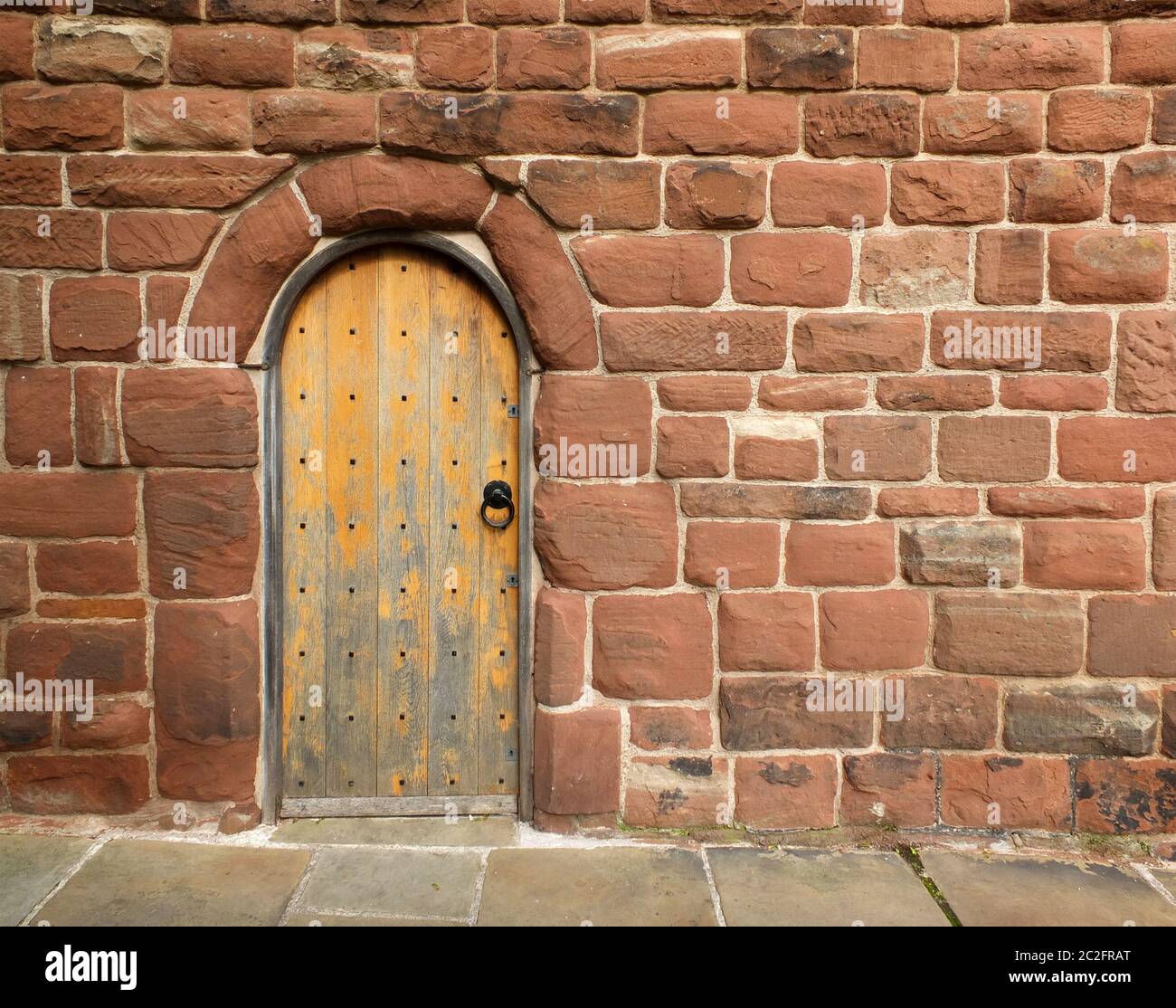 une ancienne porte en bois marron dans un mur médiéval en grès rouge Banque D'Images