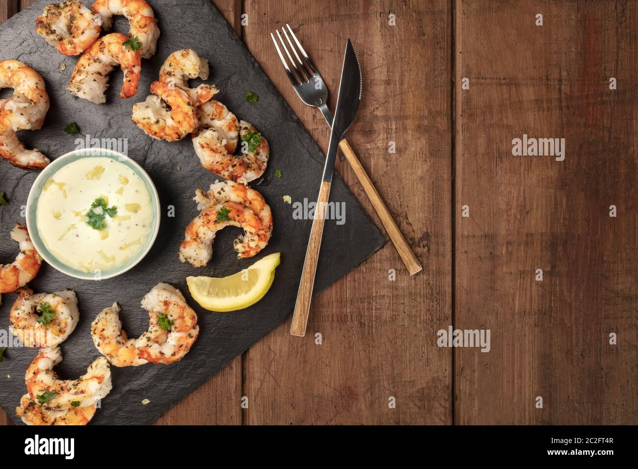 Crevettes frites avec une sauce caesar et citron, tourné par le haut sur un fond de bois rustique foncé avec une place pour le texte Banque D'Images