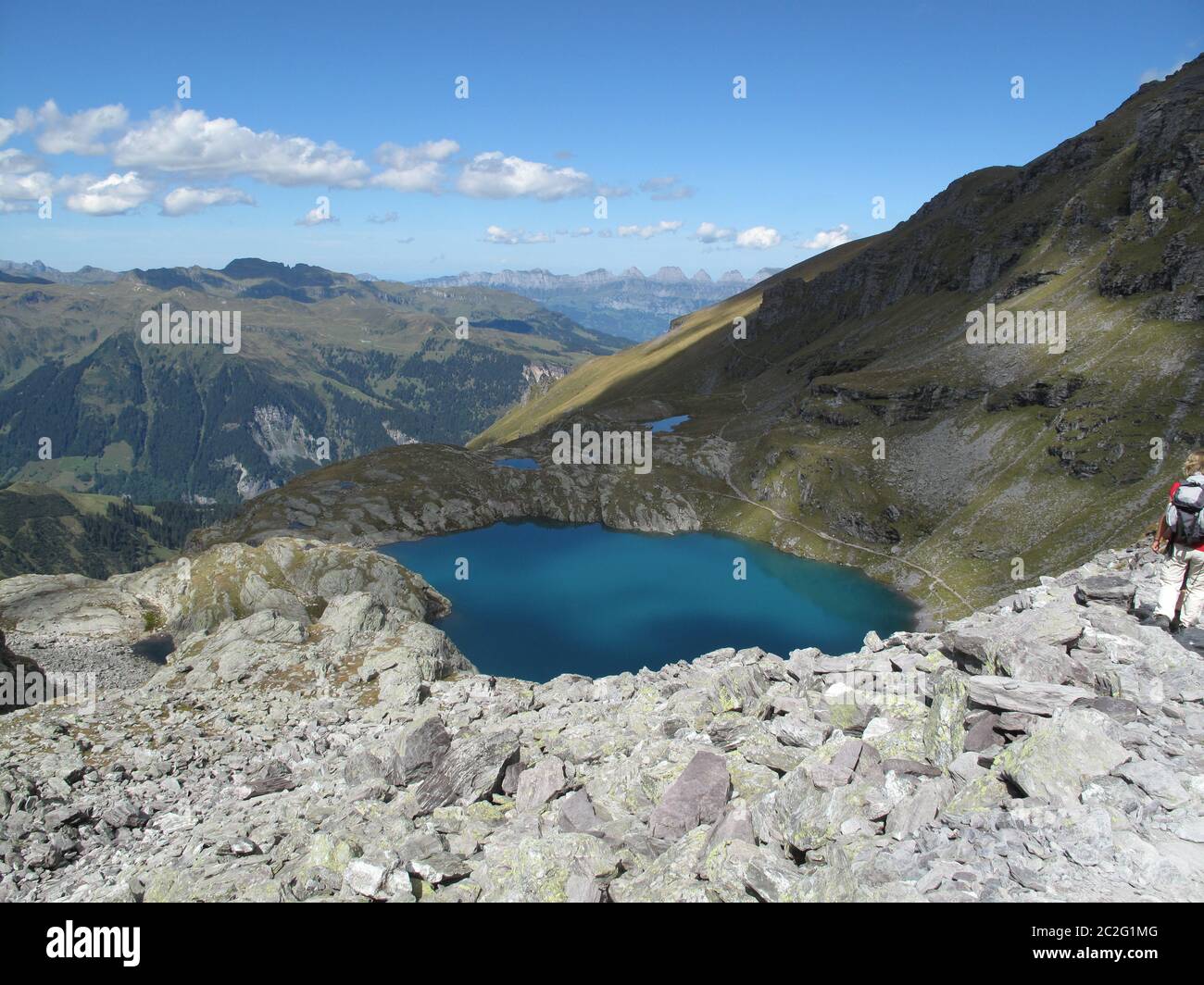 Les sommets des montagnes grises, le coton des nuages et un ciel bleu profond se reflètent dans le lac alpin turquoise ensoleillé Banque D'Images