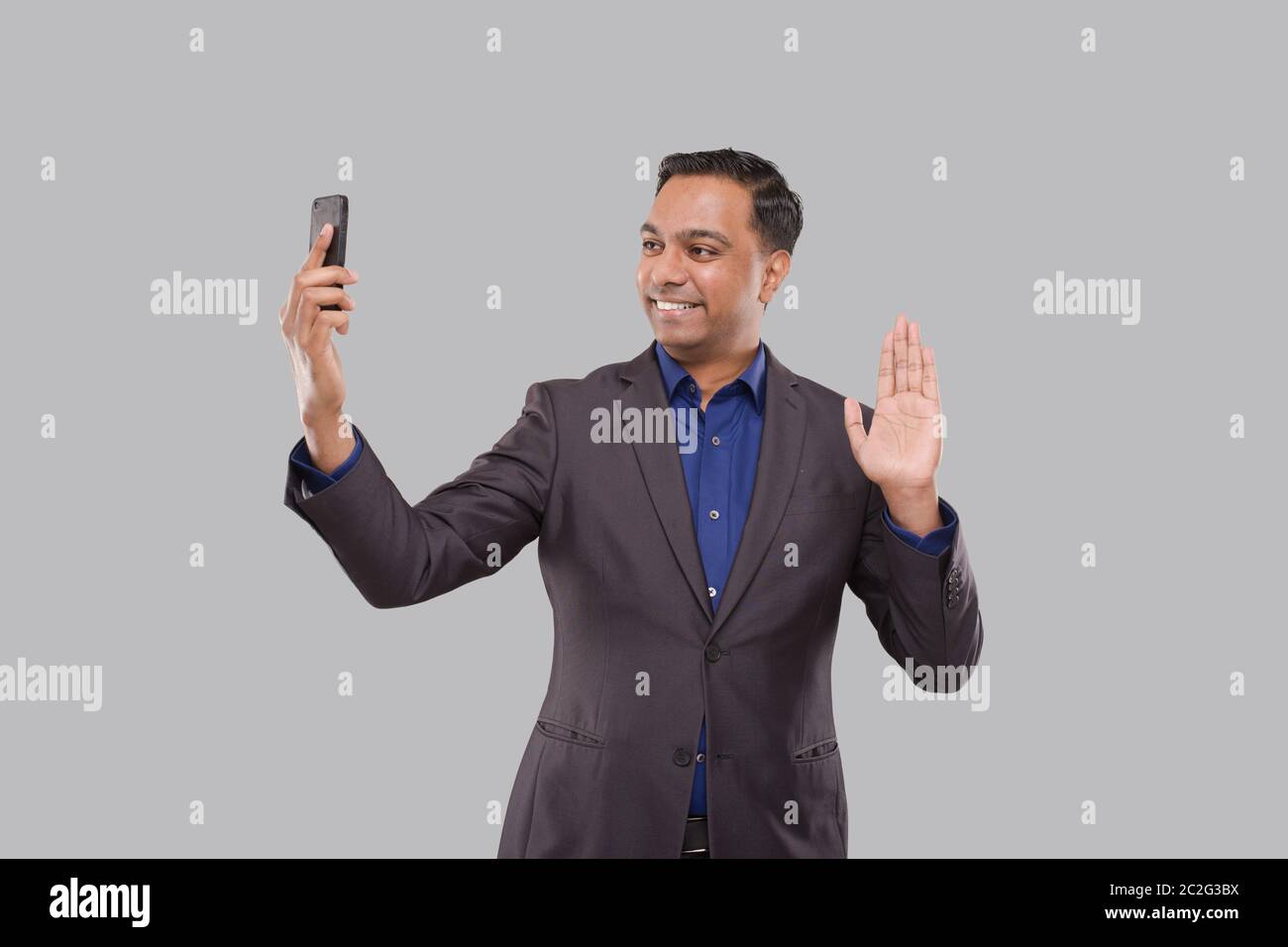Homme d'affaires ayant appel vidéo au téléphone agitant isolé. Appel vidéo homme d'affaires indien. Business Online. Homme d'affaires utilisant le téléphone. Entreprise indienne Banque D'Images