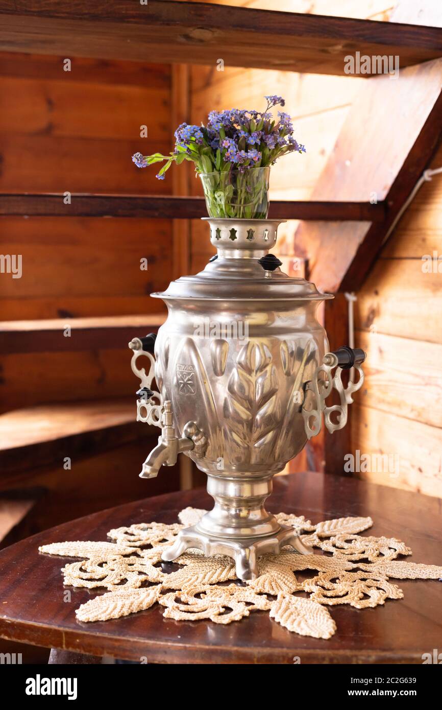 Vieux samovar en métal et un bouquet de fleurs bleues sur fond de bois Banque D'Images