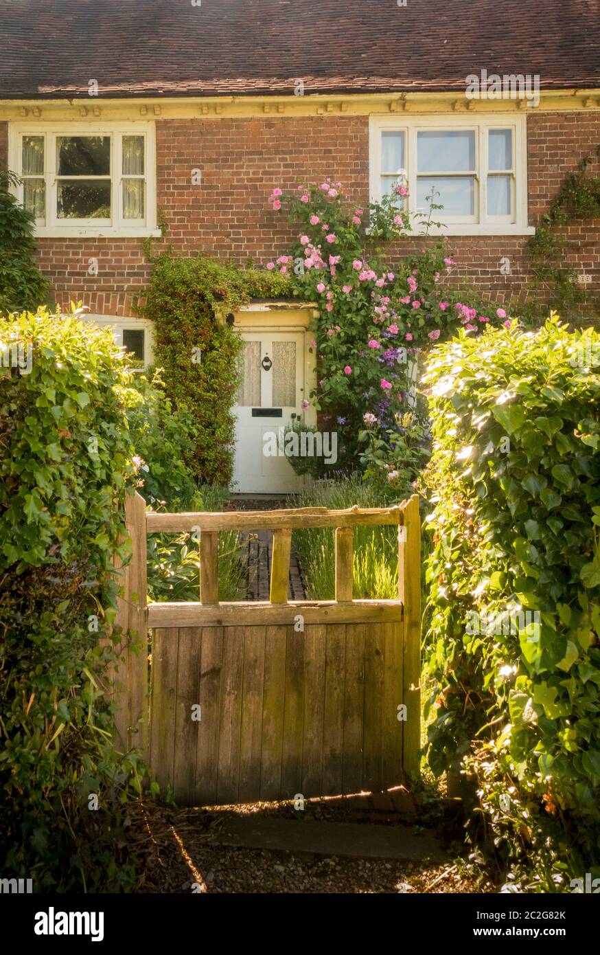 Entrée fermée à un jardin avec des roses rose autour de la porte avant Banque D'Images