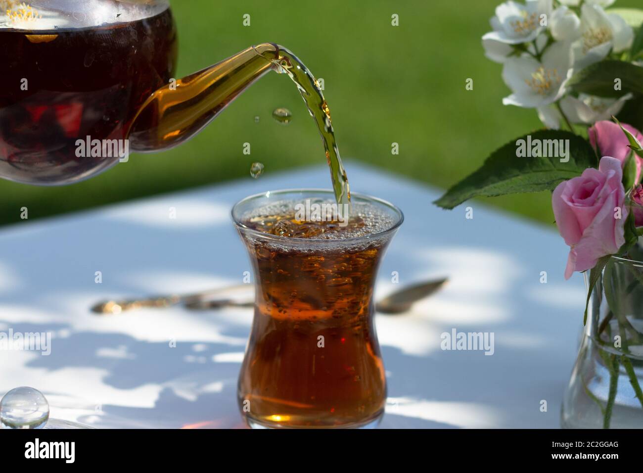 Thé de la théière verse dans le verre armudu. Banque D'Images